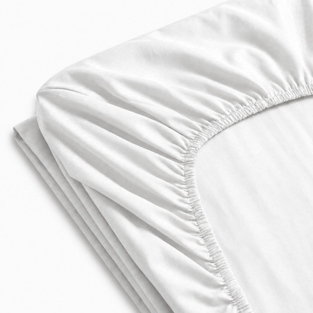 Drap-housse uni en percale de coton 100 fils/cm² avec texture lisse et maintien optimal