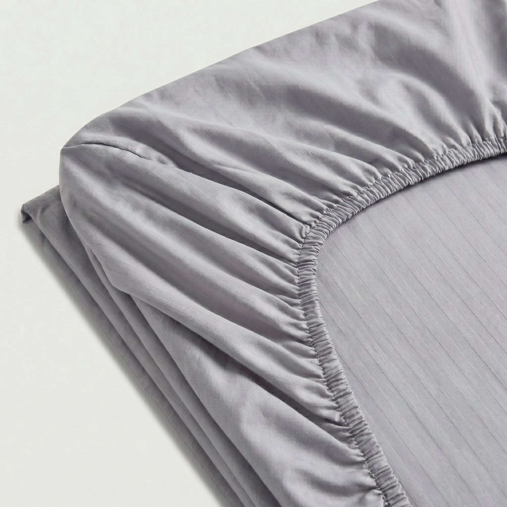 Drap-housse satin premium à fines rayures élégantes et texture soyeuse en coton.