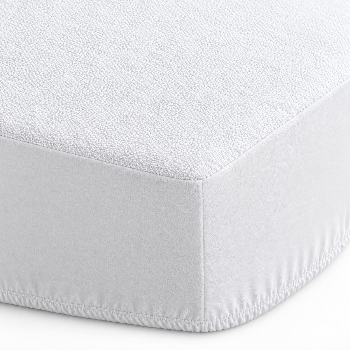 Coin du protège-matelas en éponge : dessus éponge, côtés en jersey et élastique sous le matelas comme un drap-housse