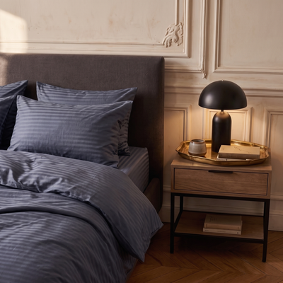 Table de chevet avec lampe noire à côté du lit habillé de satin de coton Gris Bleuté